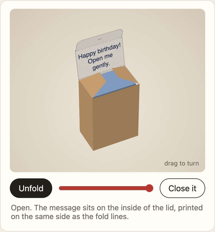An open brown box with Happy birthday! Open me gently printed inside its raised lid, above Unfold and Close it controls.