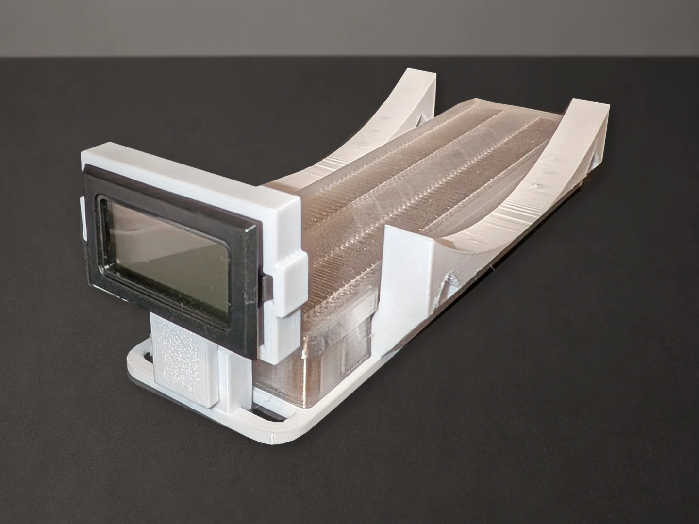 White printed spool cradle with a rectangular black-framed meter at the front and a translucent slotted tray between the curved supports.