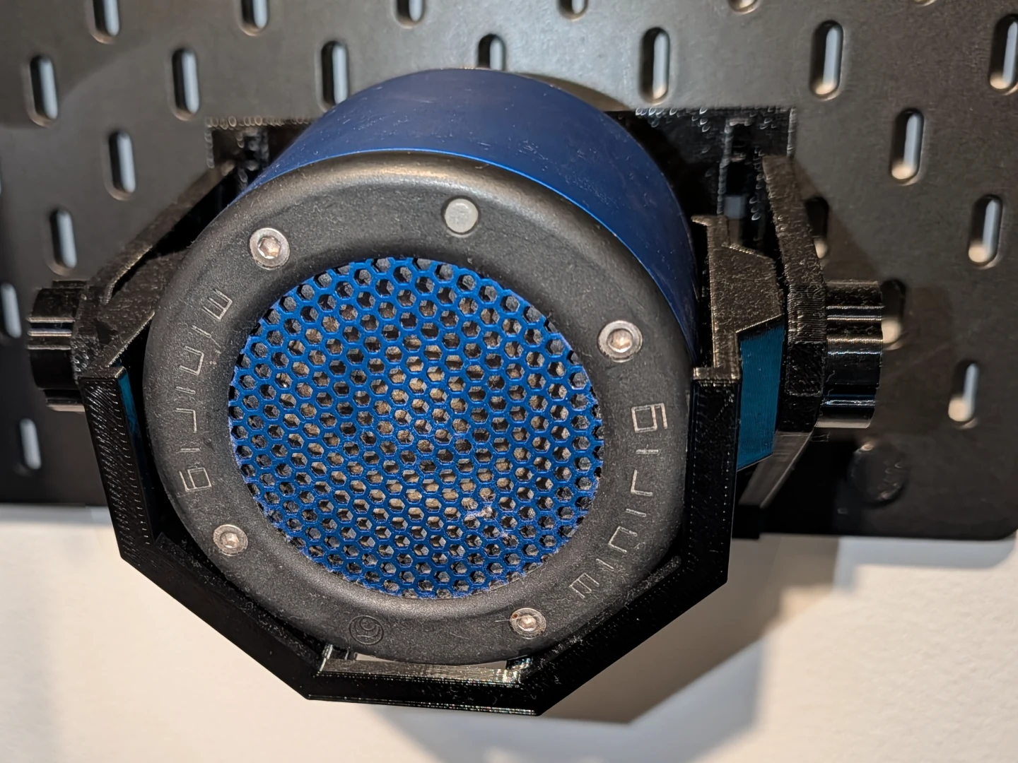 Blue Minirig speaker seated in a black printed cradle mounted on SKÅDIS, with knobs on either side.